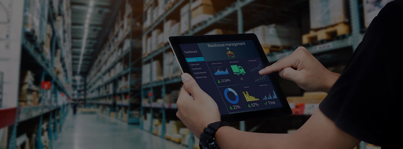 Person bedient ein Tablet mit Lagerverwaltungs-Dashboard vor Regalen in einem Lager